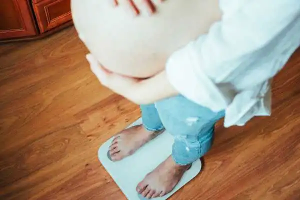 Image of woman weighing herself and experiencing weight gain through pregnancy Handsworth